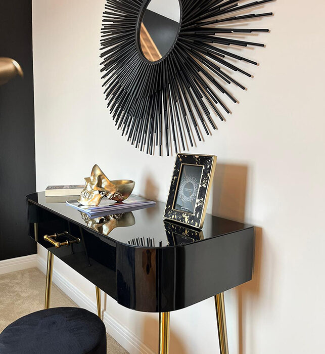 black side table with black mirror and gold accessories