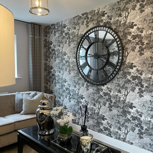 Grey floral wallpapered wall with large mirrored clock with black detailing